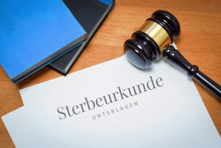 Ein Richterhammer liegt auf einem Papier mit dem Schriftzug "Sterbeurkunde"