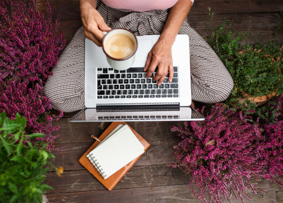 Kundencenter Mitarbeiterin in karierten Hosen arbeitet am Laptop mit Kaffeetasse.